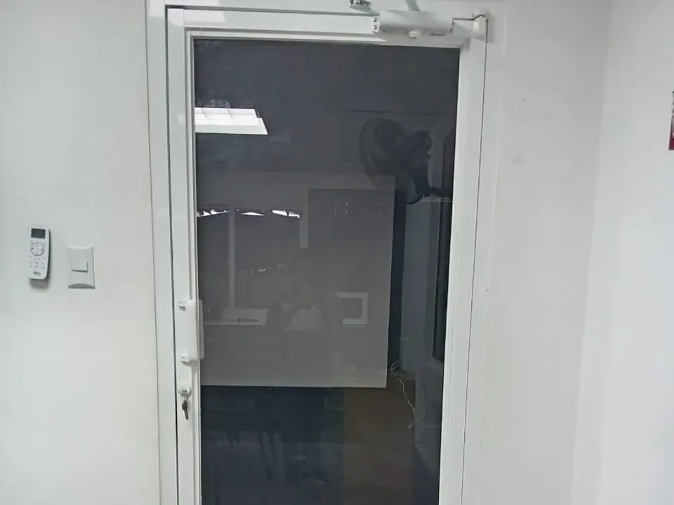 Puerta de oficina de vidrio gris con marco de aluminio blanco, cerradura y cierrapuertas hidráulico